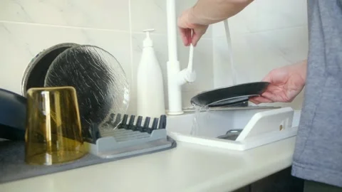 Man washing a black plate in the kitchen sink Stock Footage 337831053