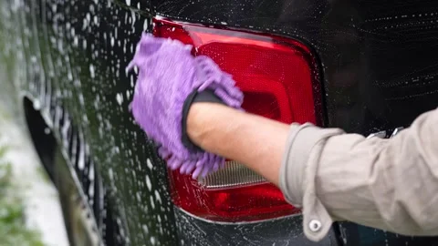 Man washing car stop light with hand, using sponge, close-up Stock Footage 282775491