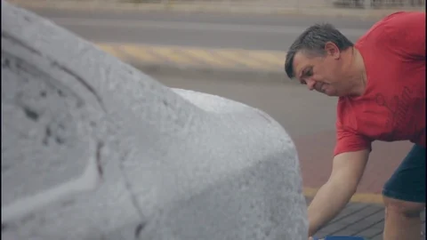 A man washing a car using a stream of water Video stock 117112643