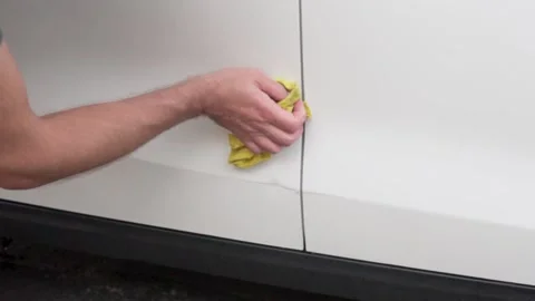 Man washing dirt from a small dent on a car Stock Footage 255483325