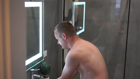 Man washing face under running cold water from faucet. Morning skincare routine. Stock Footage 157642751