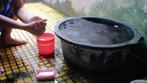 Man washing his hands with soap in a bucket of water Stock Footage 320918709