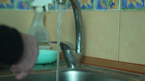 A man washing his hands under a kitchen faucet after washing a plate Vídeos de archivo 335940786