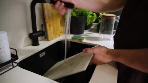 Man washing a plastic cutting board in the kitchen sink Stock Footage 345733444