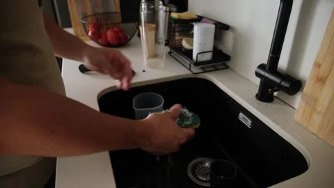 Man washing reusable plastic shaker cup in a modern kitchen sink Stock Footage 345733692