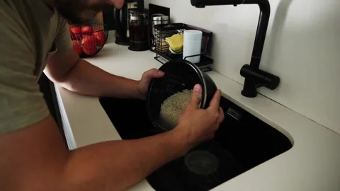 Man washing rice in a modern kitchen sink Stock Footage 345733286