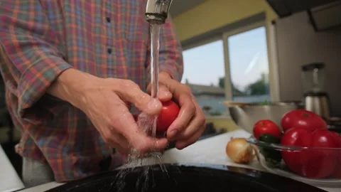 Man washing vegetables for salad. Authentic lifestyle kitchen scene. Stock Footage 316830839