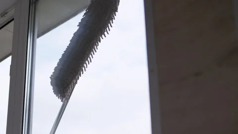 A Man Washing Windows on a Balcony with a Mop and Microfiber Cloth. Zoom Stock Footage 209169589