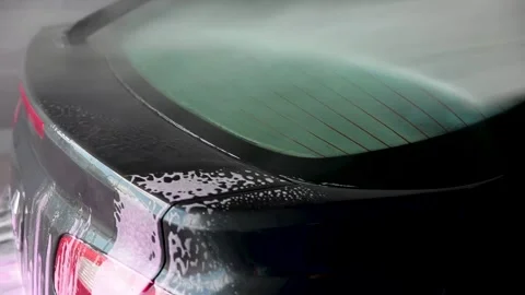 Man washing the windscreen of his car in a cubicle with a high pressure water Stock Footage 157783423