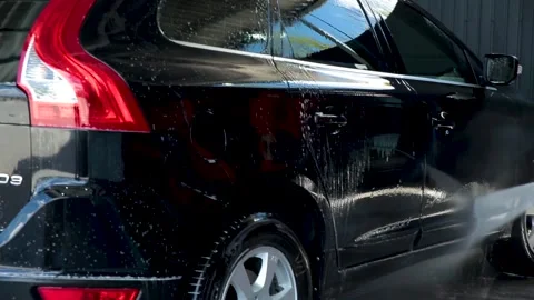 Man washing the windscreen of his car in a cubicle with a high pressure water Stock Footage 157788240