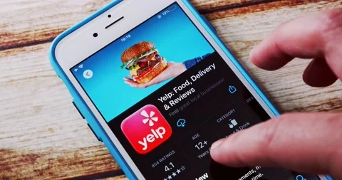 Man watches introduction of Yelp app in App Store on an iPhone Stock Footage