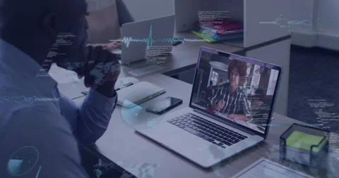 Man watching laptop as caller speaking starting tech graphs moving across desk Stock Footage 331047985