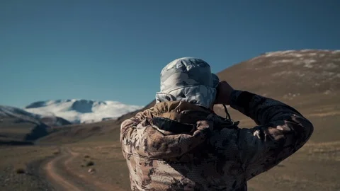 Man is watching mountain sheep through his binoculars. Study of argali Vídeo Stock 97736666