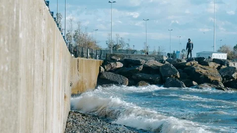 Man watching slow motion waves crashing over seawall at daytime in Istanbul Stock Footage 121533151