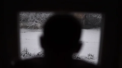 A man watching the snow falling in the yard, the man at the window Stock Footage 114630921