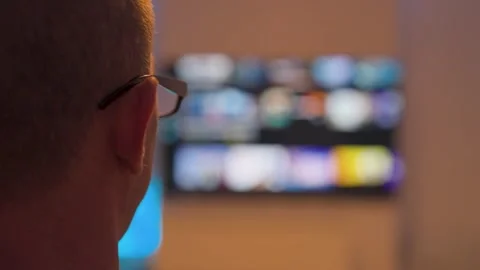 Man watching streaming tv with blurred colorful thumbnails Stock Footage 330089416