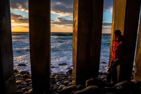 Man watching sunset between stone pillars on rocky beach in Japan Stock Photos