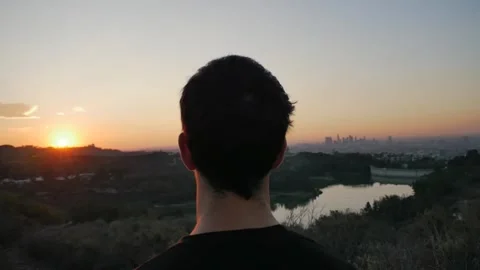Man Watching Sunset Over City and Lake from Hill Stock Footage 327445694
