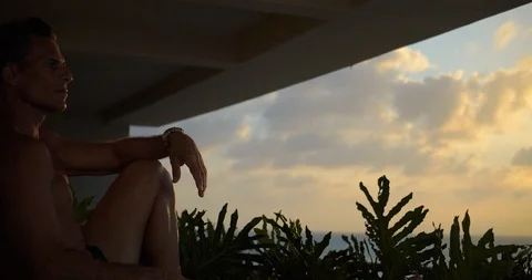 Man Watching Sunset over Ocean from Hotel Balcony 動画素材 103220748
