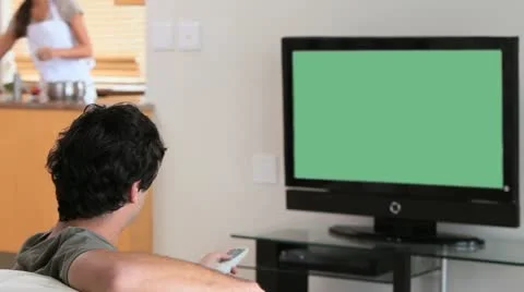 Man watching the television while his wife is cooking Stock Footage 10815047