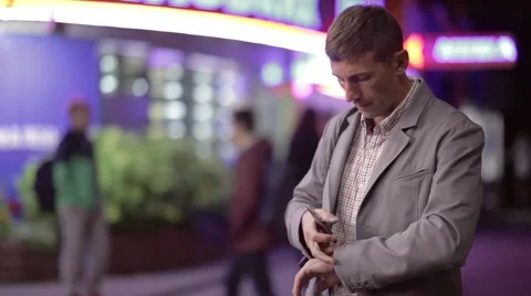 A man is watching time and typing sms in public place Stock Footage 57850147