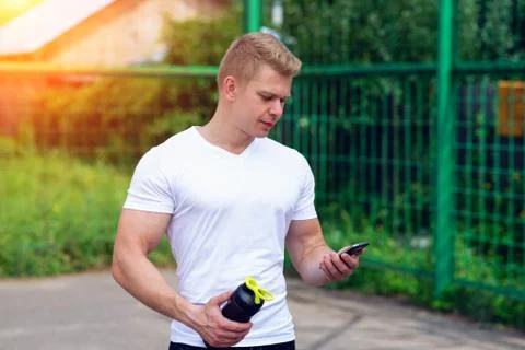 The man is watching timer on the phone, social networks, hand a shaker, a bottle 스톡 사진