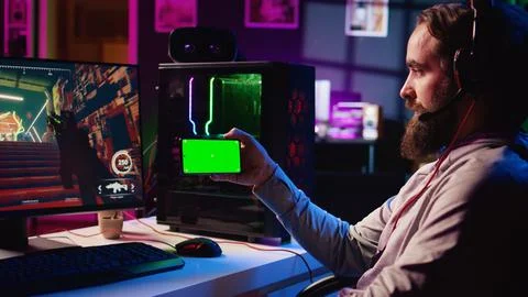 Man watching tutorial on mockup phone while playing first person shooter Stock Photos