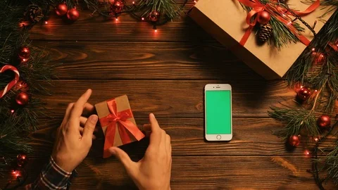 Man watching tutorial video haw to make a bow tie on a present box. Christmas Stock Footage 80903108