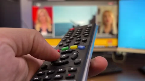 A man watching TV changes channels with the TV remote control in his hand Stock Footage 257320889