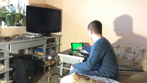 Man watching tv at home. the guy is looking for info on the tablet. hromakey Stock-Footage 103546183