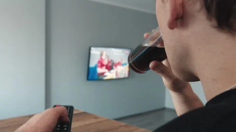 Man watching TV programs, drinking a drink, side view Stock Footage 163854176