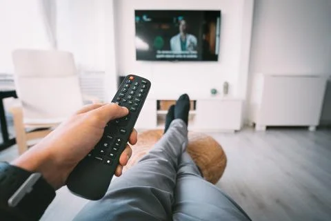 Man watching TV with remote controller in his hand. Rest at home. Stock Photos