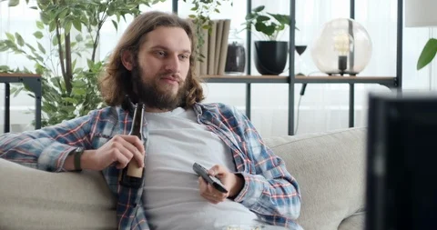 Man watching tv while drinking beer and eating popcorn at home Video stock 126054797