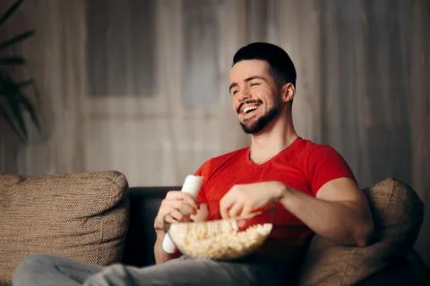 Man Watching TV While Snacking on Pop Corn Stock Photos