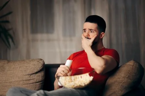 Man Watching TV While Snacking on Pop Corn Stock Photos