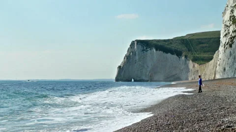 Man watching the waves on a stoney beach Stock Footage 57356097