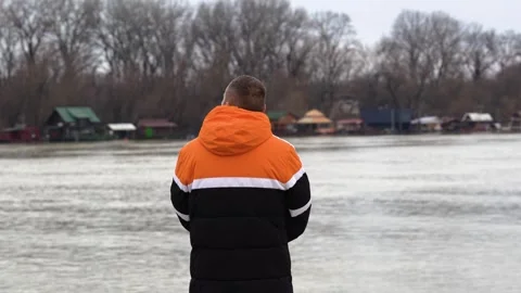 Man Watching Winter River - Contemplative Scene of Relaxation and Nature Stock Footage 330489866