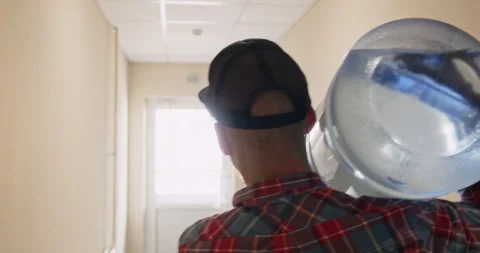 Man with water bottle walks down corridor towards light Video stock 294601689