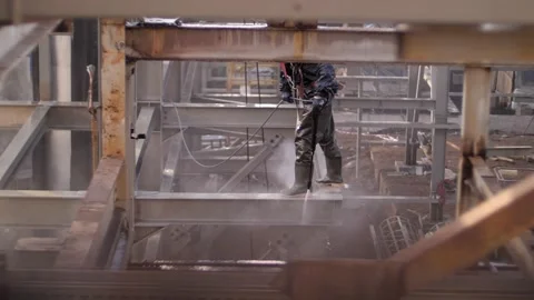 A man with a water pressure compressor washes scaffolding at a height. Stock Footage 229556217