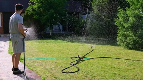 Man is watering the grass. automatic watering of the lawn in the yard with an Stock-Footage 242098861