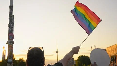 Man wave rainbow flag. Sunset silhouette Beautiful lgbt symbol. Gay pride parade Photos
