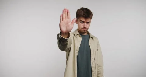 Man waves hand and smiles in bright studio setting during casual interactio.. Vidéo 326788339