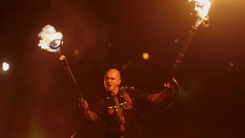 A man waving a flamethrower against the backdrop of fiery jets. Action in Stock Footage