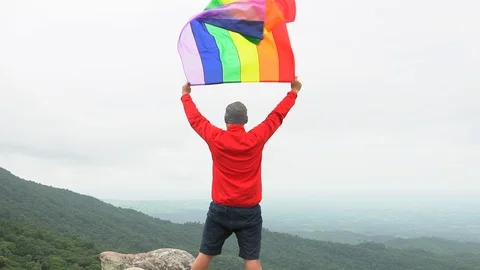 Man waving rainbow flag on mountain top Stock Footage 92154582
