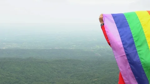 Man waving rainbow flag on mountain top Stock Footage 92154824