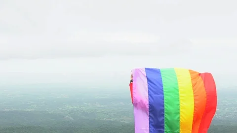 Man waving rainbow flag on mountain top Stock Footage 92155366