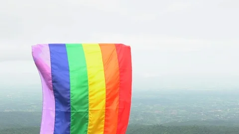 Man waving rainbow flag on mountain top Stock Footage 92155368
