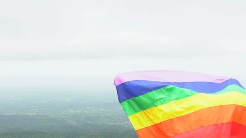 Man waving rainbow flag on mountain top Stock Footage 92156437