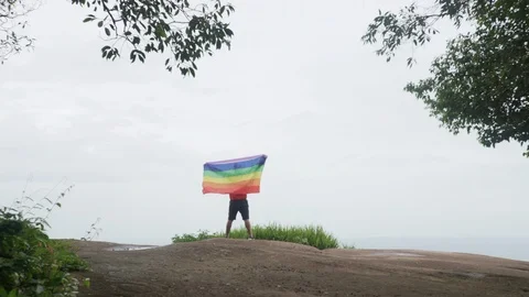 Man waving rainbow flag on mountain top Stock Footage 92247239