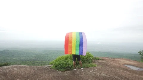Man waving rainbow flag on mountain top Stock Footage 92248383